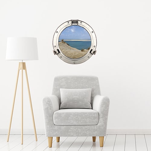 Adhésif déco mural fenêtre ronde en trompe-l'oeil comme un faux hublot de bateau avec vue sur les dunes du pilat dans un intérieur déco sobre et tendance.