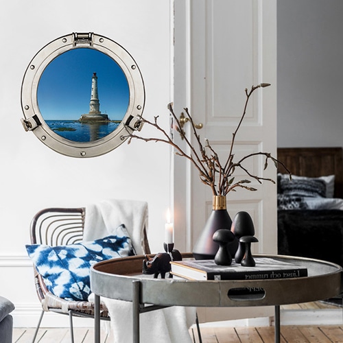 Décoration marine dans une joli salon tendance avec une fausse fenêtre ronde de hublot de bateau avec vue sur un phare marin.