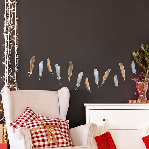 Décoration mural avec des Sticker Plumes Or et Argent sur un mur noir au-dessus d'un fauteuil blanc