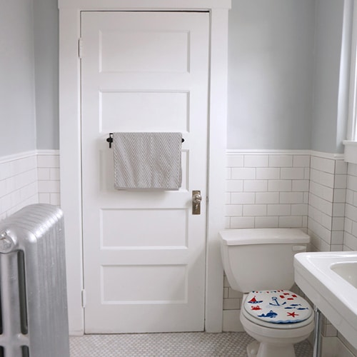 Sticker adhésif décoratif motif chevrons horizontaux chevrons blanc et noirs collé sur la vitre d'une petite douche dans une petite salle de bain avec WC