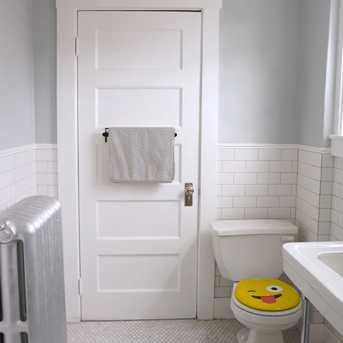 Sticker Smiley jaune qui tire la langue collé sur des WC