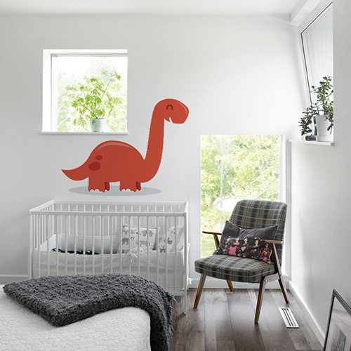 Sticker dinosaure rouge enfant avec ombre sur mur blanc au dessus d'un berceau