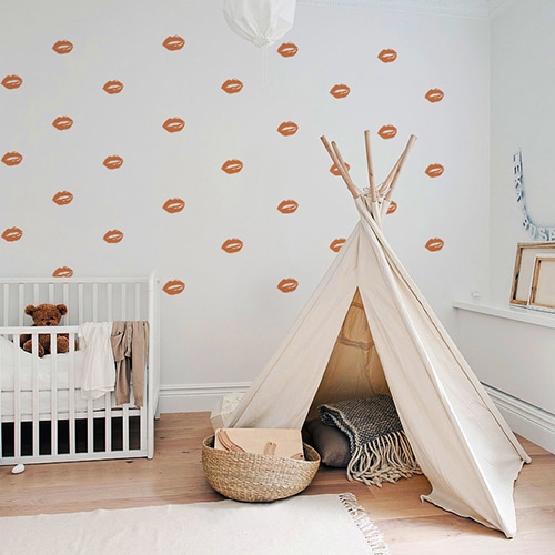 Stickers lèvres oranges mis en mosaïque sur un mur clair d'une chambre d'enfants