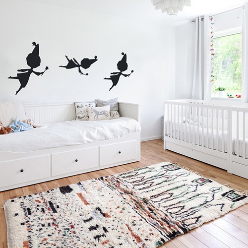 trois stickers muraux fées noires mis en ambiance sur un mur blanc d'une chambre de bébé