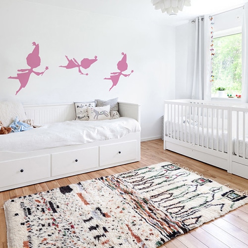 trois stickers muraux fées roses mis en ambiance sur un mur blanc d'une chambre de bébé