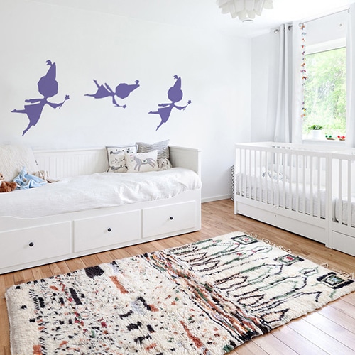 trois stickers muraux fées violettes mis en ambiance sur un mur blanc d'une chambre de bébé