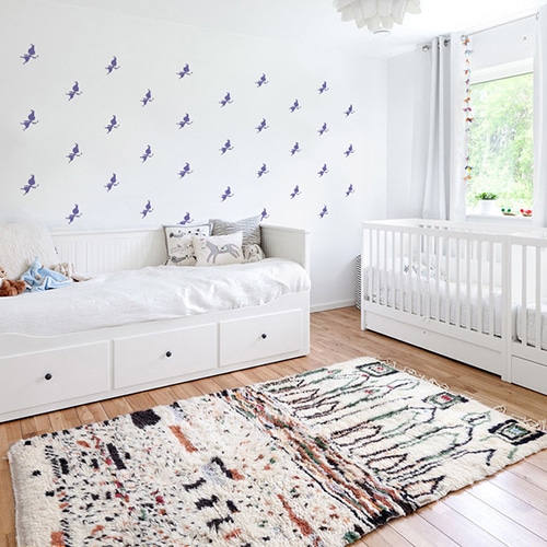 Mosaïque de stickers fées violettes sur mur blanc dans une chambre de bébé