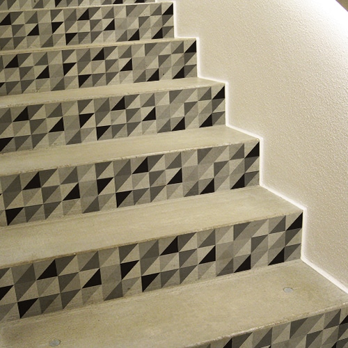 Autocollants escaliers motif triangles emboités noir blanc et gris sur escaliers classiques