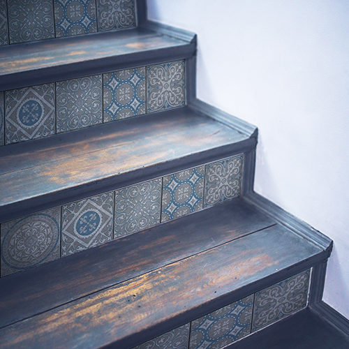 Egayez un esclaier en bois avec des contremarches adhésives pour escalier carreaux de ciment bleu et gris.