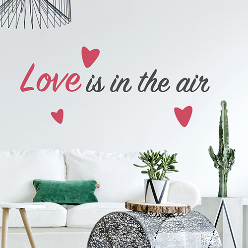 Citation d'amour Love is in the Air collé sur le mur d'une pièce à vivre