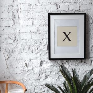 Autocollant "X" lettre d'alphabet beige et noir pour décoration de cadre sur un mur blanc