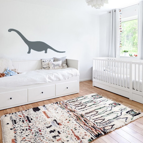 Chambre d'enfant avec un mur orné d'un sticker dino gris géant