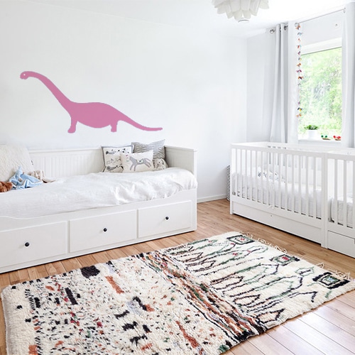 sticker géant dino rose collé au mur d'une chambre pour décorer