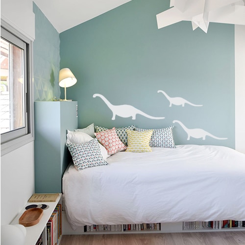 Ensemble de trois stickers dino gris clair collés au mur d'une chambre