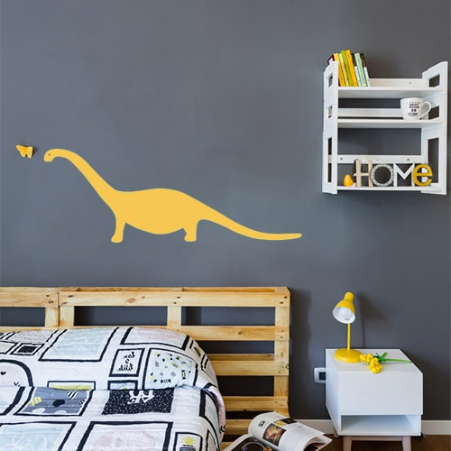 Sticker autocollant dinosaure jaune collé au mur gris foncé d'une chambre