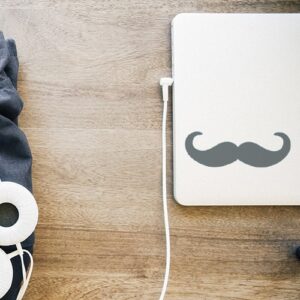 sticker décoratif moustache grise foncée en croc posée sur un pc portable