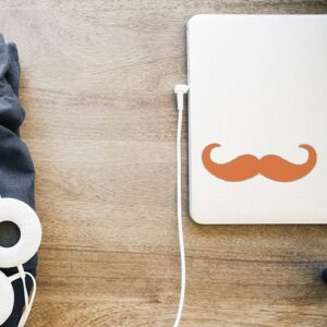 sticker décoratif moustache en croc orange collé sur un ordinateur de bureau