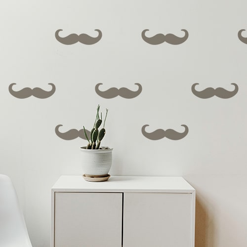 Frise de stickers adhésifs moustache en croc couleur taupe sur un mur blanc d'une pièce à vivre