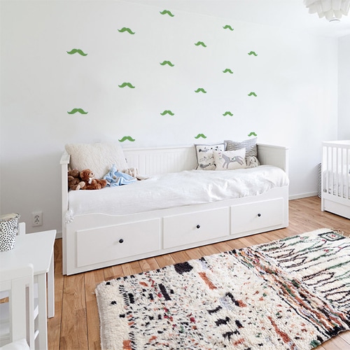 sticker frise de petites moustaches verte collées au mur d'une chambre seule