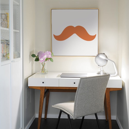 sticker moustache épaisse orange collé sur un tableau mural