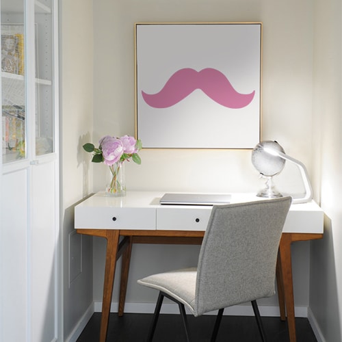sticker moustache épaisse rose sur un tableau au mur