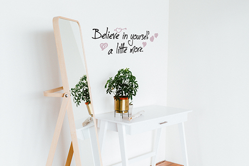 Sticker citation manuscrite Believe in yourself colorée collé au mur blanc d'un dressing