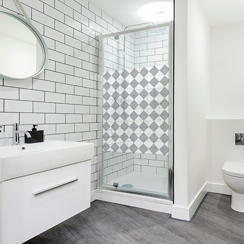 sticker décoratif adhésif motif damier gris et blanc format carré collé sur la vitre d'une douche moderne dans une salle de bain éclairée et lumineuse