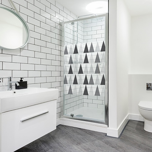 sticker format carré décoratif autocolnt motif triangles noirs blanc et gris collé sur la porte vitrée de la douche d'une salle de bain blanche et moderne (avec WC)