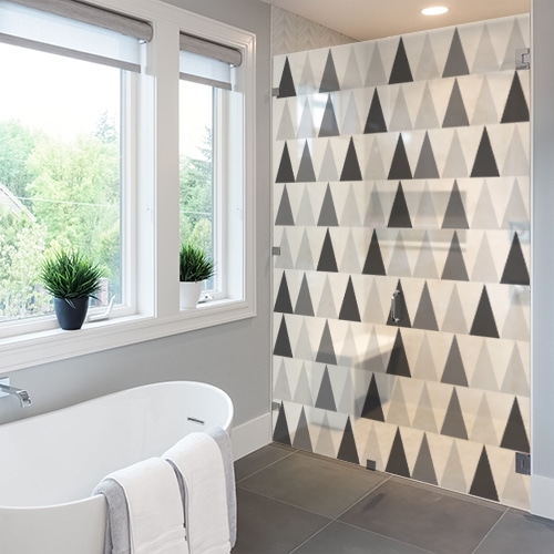 sticker décoratif adhésif motif triangles noirs blanc et gris collé à la vitre d'une salle de bain luxueuse avec baignoire