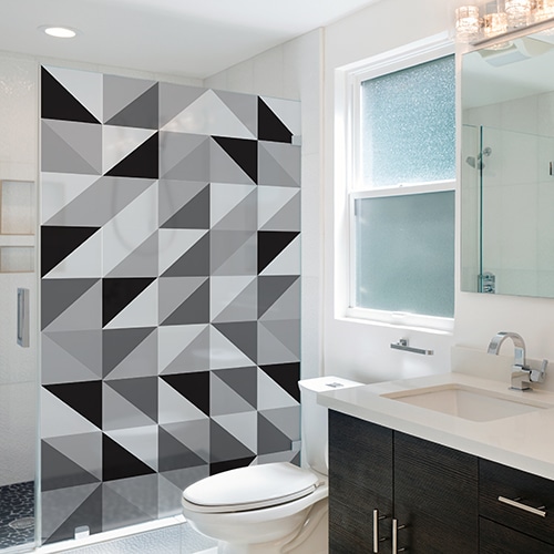 Sticker décoratif autocollant motif triangles noirs, blancs et gris collé sur une baignoire douche dans une petite salle de bain