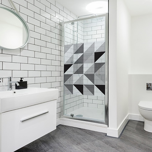 Sticker format carré décoratif adhésif motif triangles tri-color collé sur une vitre dans une salle de bain moderne