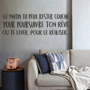 Sticker "le matin tu peux rester couché pour poursuivre ton rêve ou te lever pour le réaliser" collé sur un mur de salon cosy