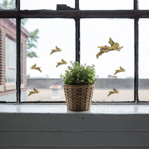 Stickers angelots collés sur une fenêtre vintage devant une plante verte