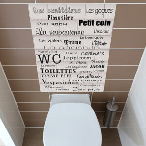 Autocollant adhésif mural plusieurs mot décrivant le mot toilette collé dans une salle de toilette