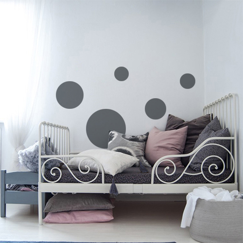 Autocollant décoratif rond gris foncé pour déco de mur blanc dans une chambre d'enfant