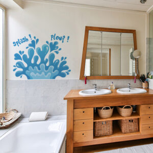 sticker plouf sur un mur de salle de bain lumineuse avec des meubles en osier