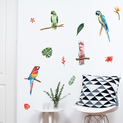 Jolis stickers muraux exotiques représentant des perroquets et autres éléement tropicaux posés sur un mur blanc dans un intérieur scandinave.