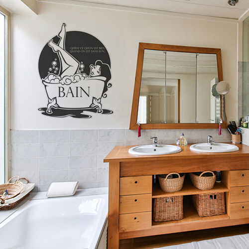 sticker décoratif bain citation et graphisme apposé sur les murs d'une salle de bain avec les meubles en osier