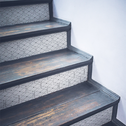 Stickers adhésifs blancs recouvert de motifs noirs collés sur des escaliers en bois traditionnels
