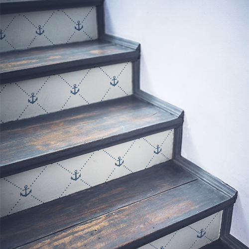 Frises d'ancres bleues sur fond blanc posées sur un escalier en bois noir