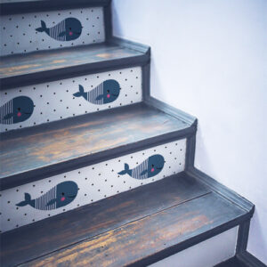 Escalier en bois noir orné de plusieurs stickers pour enfants représentant des baleines
