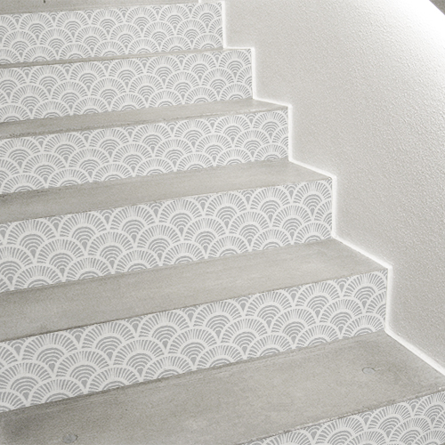 Zoom sur une déco d'escalier discrète et jolie grâce aux stickers pour contremarches motif écailles rayées gris et blanc.