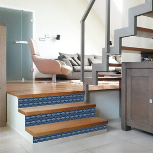 Les escaliers en bois clair sont personnalisés avec l'aide de jolies contremarches adhésives écailles sirène en camaïeu de bleu.