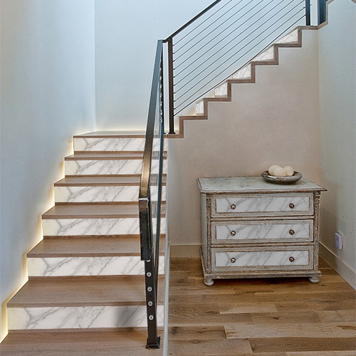 Décoration des contremarches d'escalier avec des adhésifs effet marbre blanc et personnalisation des tiroirs de commode assortis.