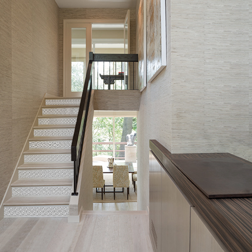 Cage d'escalier maison moderne avec contremarches personnalisées au motif ethnique losange noir et blanc.