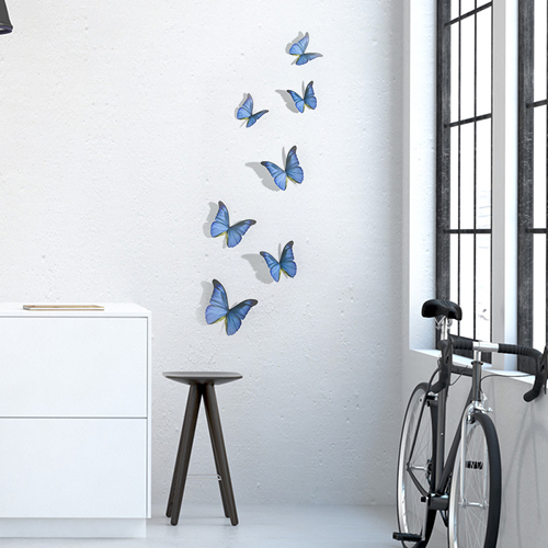 Sticker autocollant mural représentant des papillons bleu cobalt dans un salon avec un vélo et une table basse