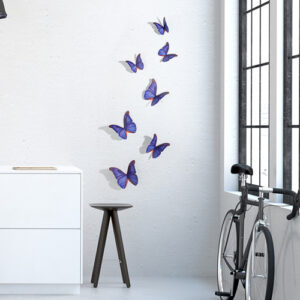Sticker papillons bleu indigo déco sur un mur blanc de salon avec un vélo et une table basse