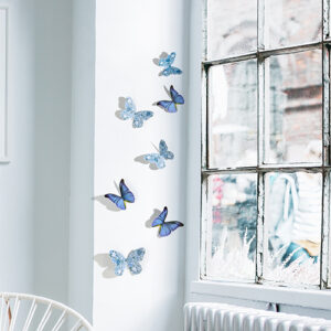 Sticker autocollant Papillons bleu et liberty sur un mur blanc à côté d'une fenêtre