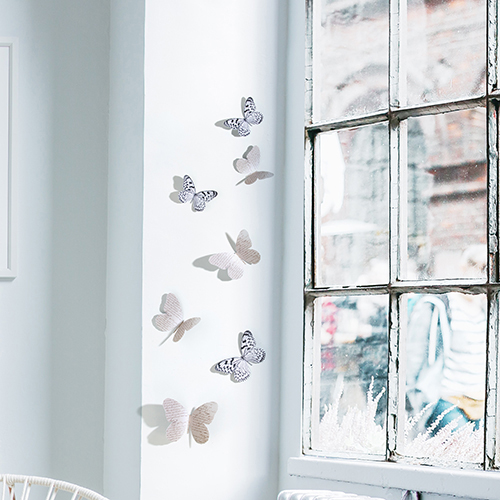 Sticker mural adhésif 3D papillons bleu collés sur un mur blanc