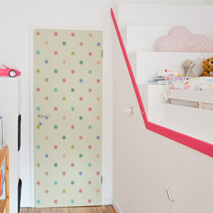 Chambre d'enfants dont la porte est décorée par un sticker autocollant multicolores à pois